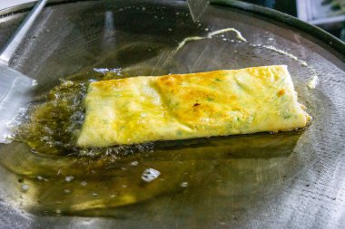 Şef geleneksel Endonezya yemeği olan yumurta martabak pişiriyor. Sebzeler, et ve çeşitli baharatlar ince bir hamur kabuğuna sarılıp kızartılır.