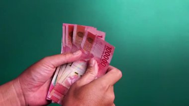 Eller yeşil bir geçmişi olan Endonezya para birimini sayıyor.