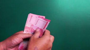 Eller yeşil bir geçmişi olan Endonezya para birimini sayıyor.