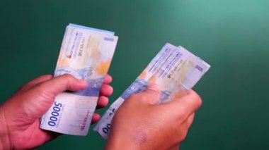 Eller yeşil bir geçmişi olan Endonezya para birimini sayıyor.