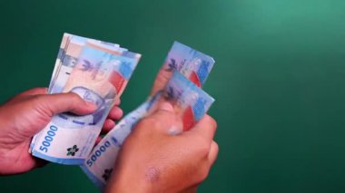 Eller yeşil bir geçmişi olan Endonezya para birimini sayıyor.