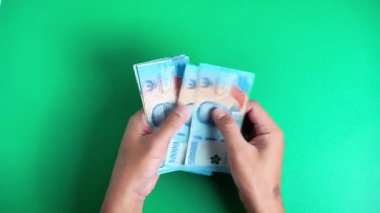 Eller yeşil bir geçmişi olan Endonezya para birimini sayıyor.