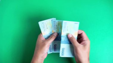 Eller yeşil bir geçmişi olan Endonezya para birimini sayıyor.