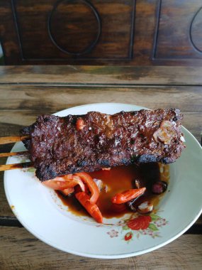 Satay sapi (sığır şişi). Soya sosu, acı biber ve domates ile servis edilir. Satay, Endonezya kökenlidir.