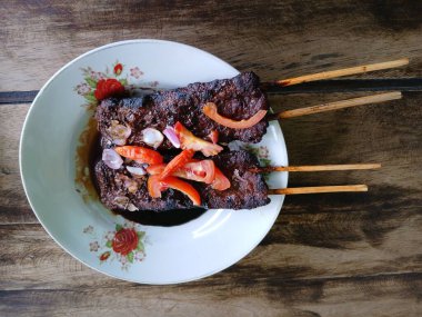 Satay sapi (sığır şişi). Soya sosu, acı biber ve domates ile servis edilir. Satay, Endonezya kökenlidir.