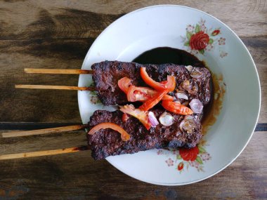 Satay sapi (sığır şişi). Soya sosu, acı biber ve domates ile servis edilir. Satay, Endonezya kökenlidir.