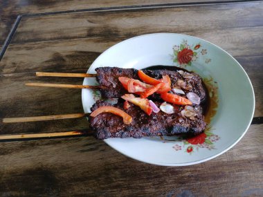Satay sapi (sığır şişi). Soya sosu, acı biber ve domates ile servis edilir. Satay, Endonezya kökenlidir.