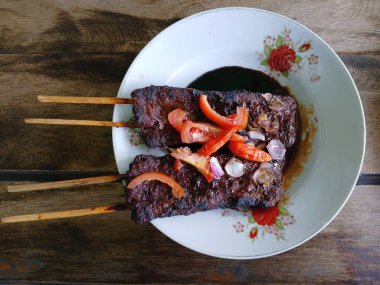 Satay sapi (sığır şişi). Soya sosu, acı biber ve domates ile servis edilir. Satay, Endonezya kökenlidir.