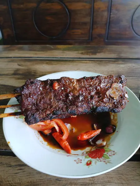 Satay sapi (sığır şişi). Soya sosu, acı biber ve domates ile servis edilir. Satay, Endonezya kökenlidir.