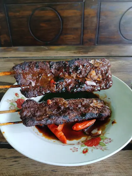 Satay sapi (sığır şişi). Soya sosu, acı biber ve domates ile servis edilir. Satay, Endonezya kökenlidir.