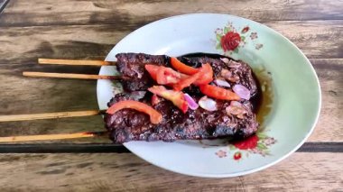 Satay sapi (sığır şişi). Soya sosu, acı biber ve domates ile servis edilir. Satay, Endonezya kökenlidir.