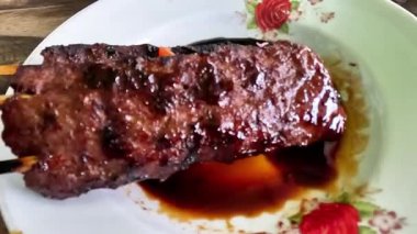 Satay sapi (sığır şişi). Soya sosu, acı biber ve domates ile servis edilir. Satay, Endonezya kökenlidir.