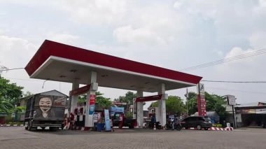 İnsanlar gün boyunca benzin istasyonunda benzin almak için kuyruğa giriyor.