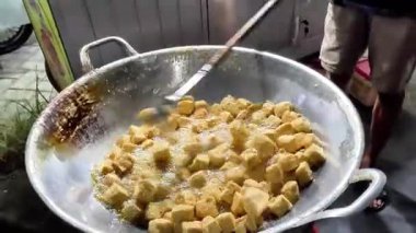 Bir satıcı müşteri için tofu pişiriyor. Endonezya sokak yemekleri.