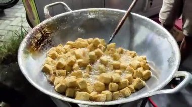 Bir satıcı müşteri için tofu pişiriyor. Endonezya sokak yemekleri.