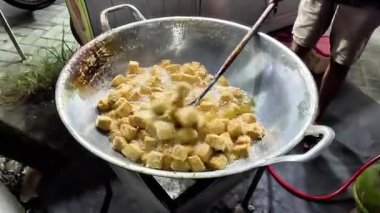 Bir satıcı müşteri için tofu pişiriyor. Endonezya sokak yemekleri.