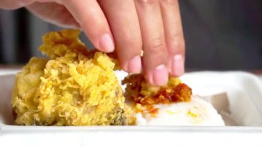 Ayam geprek yemek (Endonezya baharatlı kızarmış tavuk) pilavlı ve elleri köpüklü