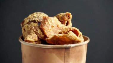 Kağıt bir kasede Keripik kulit ayam (tavuk derisi parçaları). Endonezya sokak yemekleri.