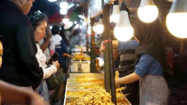 İnsanlar Kuno Kini Çarşısı 'ndan (Kediri Çarşısı) kızarmış yiyecek satın alıyor.)