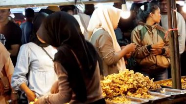 İnsanlar Kuno Kini Çarşısı 'ndan (Kediri Çarşısı) kızarmış yiyecek satın alıyor.)