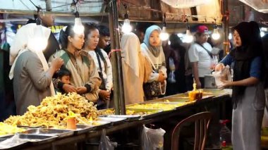 İnsanlar Kuno Kini Çarşısı 'ndan (Kediri Çarşısı) kızarmış yiyecek satın alıyor.)