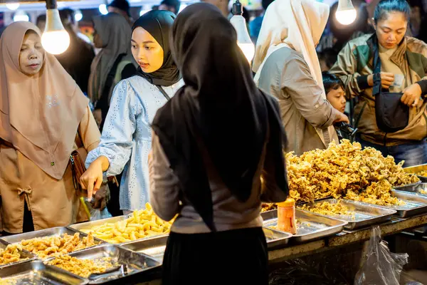 İnsanlar Kuno Kini Çarşısı 'ndan (Kediri Çarşısı) kızarmış yiyecek satın alıyor.)