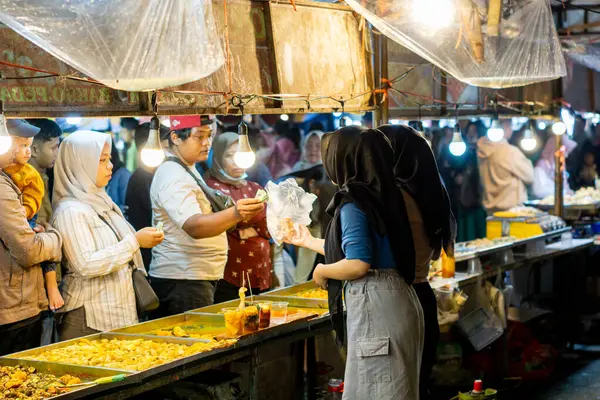 İnsanlar Kuno Kini Çarşısı 'ndan (Kediri Çarşısı) kızarmış yiyecek satın alıyor.)