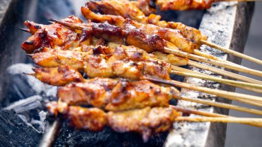 Şef kömürle pişirilmiş sate ayam (tavuk şişi). Fıstık soslu Sate Ayam..