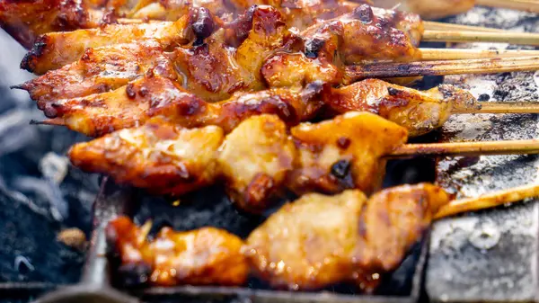 Şef kömürle pişirilmiş sate ayam (tavuk şişi). Fıstık soslu Sate Ayam..