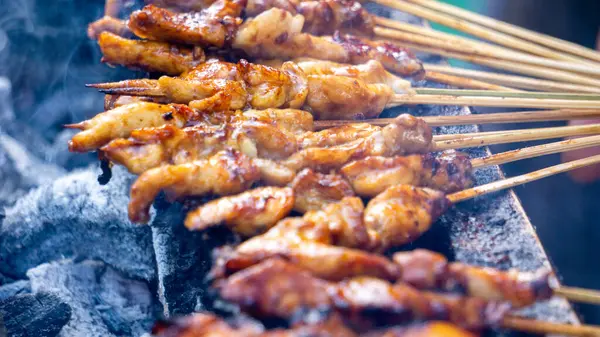 Şef kömürle pişirilmiş sate ayam (tavuk şişi). Fıstık soslu Sate Ayam..