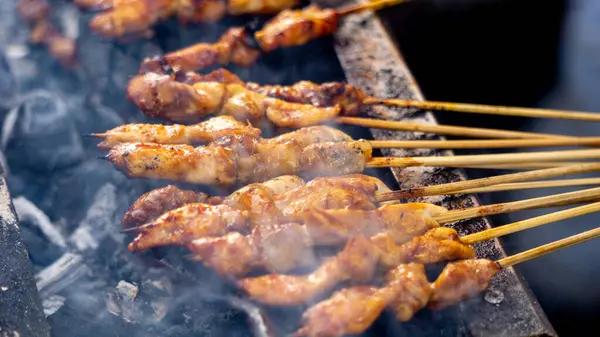 Şef kömürle pişirilmiş sate ayam (tavuk şişi). Fıstık soslu Sate Ayam..