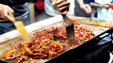 Satıcı kuyrukta bekleyen müşteriler için ızgara kalamar pişirir..