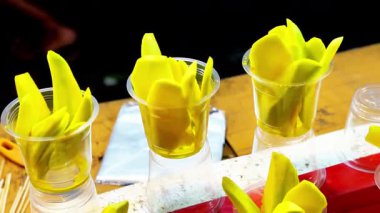 Plastik bardakta turşulu mango. Tipik bir Endonezya aperatifi, sirke, tuz, şeker ve baharat solüsyonuna batırılmış, dilimlenmiş genç mangodan yapılır..