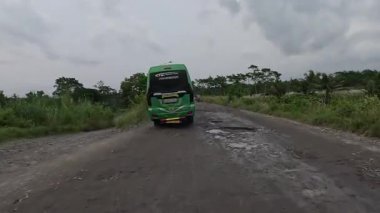Asfalt yol araçların geçtiği deliklerle dolu, bazıları kuru, bazıları su altında.