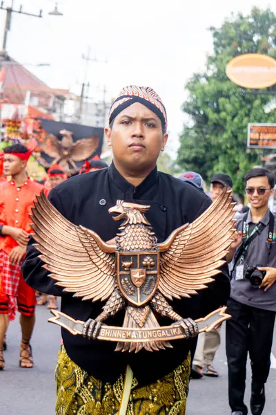 Elleri, Endonezya devletinin sembolü olan Garuda 'nın elinde..