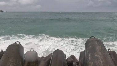 Büyük dalgalar sahildeki dalgalı kayalara çarpıyor.