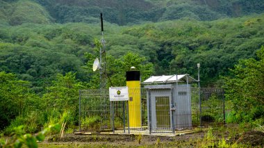 Yeşil dağ arka planına sahip Kelud Dağı kraterindeki volkanik izleme ekipmanları.