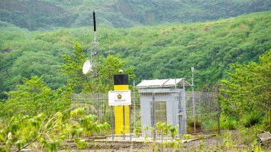 Yeşil dağ arka planına sahip Kelud Dağı kraterindeki volkanik izleme ekipmanları.