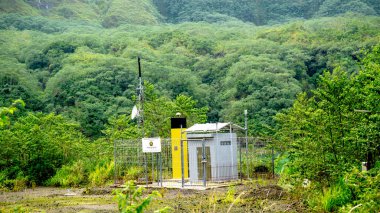 Yeşil dağ arka planına sahip Kelud Dağı kraterindeki volkanik izleme ekipmanları.