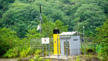 Yeşil dağ arka planına sahip Kelud Dağı kraterindeki volkanik izleme ekipmanları.