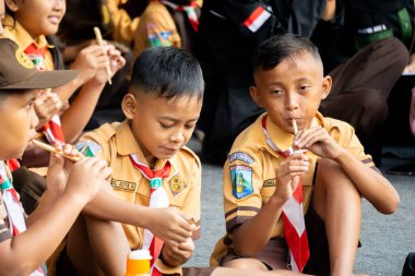 Endonezyalı izci öğrenci parkta mutlu bir şekilde bambu flütü çalıyor.