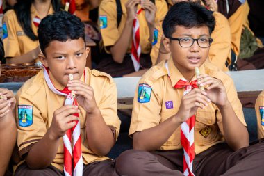 Endonezyalı izci öğrenci parkta mutlu bir şekilde bambu flütü çalıyor.