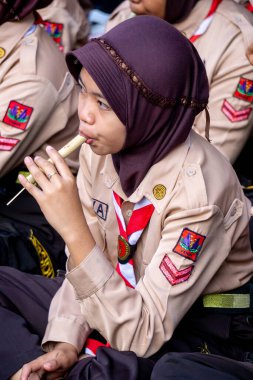 Endonezyalı izci öğrenci parkta mutlu bir şekilde bambu flütü çalıyor.