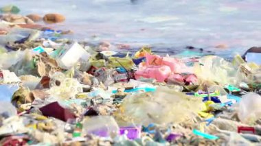 Plaja saçılmış çeşitli plastik atıklar. Çöp çevreyi kirletir ve zarar verir