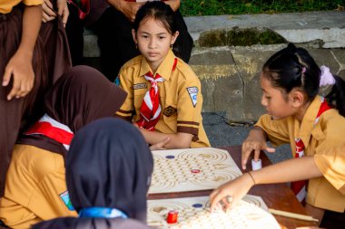 İlkokul izci üniformalı çocuklar geleneksel Endonezya oyunları oynuyor, görünüşe göre eğleniyorlar ve eğleniyorlar..