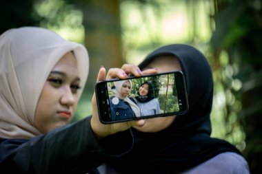 Two beautiful sibling Asian women taking a selfie together in the park.