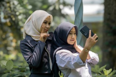 Two beautiful sibling Asian women taking a selfie together in the park.