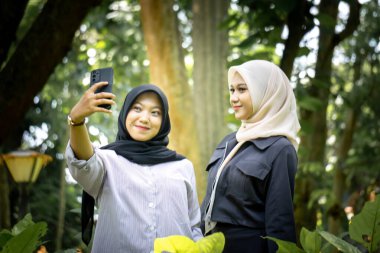 Two beautiful sibling Asian women taking a selfie together in the park.