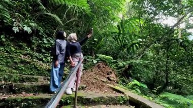 Two beautiful asian moslem girl take a picture at the green forest