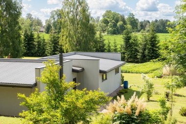 Yumuşak, tüylü bulutlarla dolu geniş bir gökyüzünün altında bakımlı ağaçlar ve yemyeşil çimlerle güzel korunan bir arazi. Huzurlu manzara huzur ve sükunet yayar, doğanın güzelliğini mükemmel bir uyum içinde gösterir..